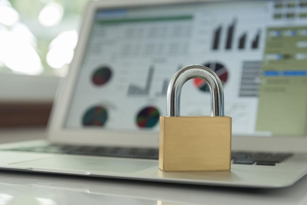 A padlock placed on a laptop displaying cybersecurity and data protection charts, symbolizing online security and data privacy.