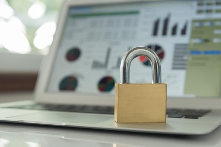 A padlock placed on a laptop displaying cybersecurity and data protection charts, symbolizing online security and data privacy.
